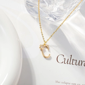 Close-up of golden letter C pendant with zircon flower detail on a delicate chain