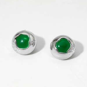 Macro shot of silver ball earrings with hammered texture and green stone inlay
