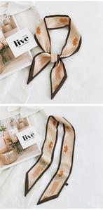 Detail of floral beige skinny silk scarf with brown trim tied and laid flat on a shirt