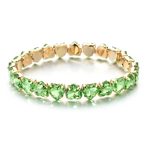 Detail shot of heart-cut green zircon stones set in a gold-plated link bracelet
