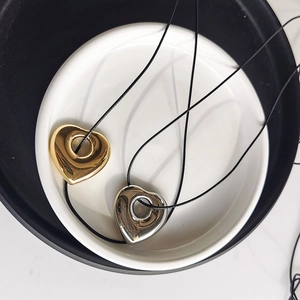 Macro shot of gold and silver hollow heart pendants with black wax cord necklaces