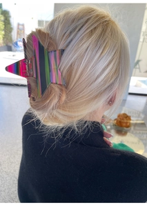 Detail of star-shaped hair claw with holographic rainbow glitter finish on a bun hairstyle