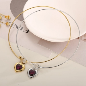 Detail of gold and silver heart pendants with purple faceted stones on rigid collars