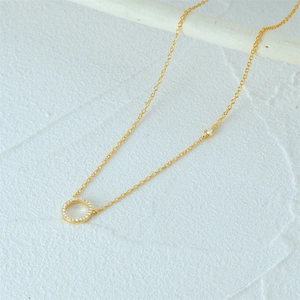 Close-up of a gold S925 sterling silver necklace with a sparkling diamond circle pendant