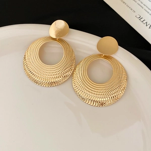 Vue macro de grandes boucles d'oreilles rondes dorées avec textures radiales en relief