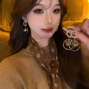 Close-up of elegant gold letter D earrings with sparkling rhinestones worn by a model