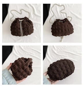 Detail view of small brown drawstring bag with pleated texture and silver chain strap