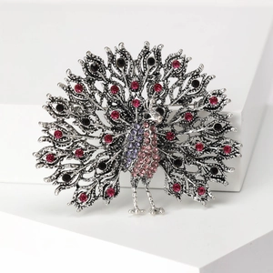 Detail of peacock brooch with sparkling pink and purple crystals on silver metal