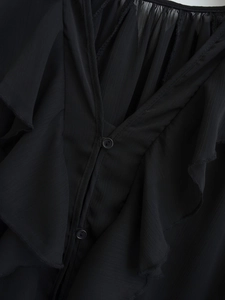 Detail of black chiffon fabric showing ruffle collar and delicate button closure