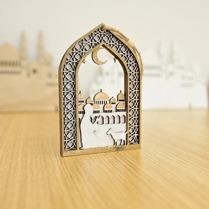 Macro shot of a wooden Ramadan crescent ornament with carved prayer scene and mosque