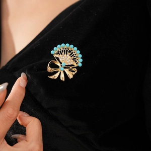 Detailed view of vintage bow fan brooch with turquoise beads and rhinestones on black velvet