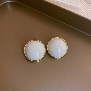Detailed view of elegant cream white pearl earrings with minimalist golden metal frames