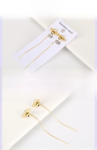 Detail of gold bee tassel earrings with black enamel stripes and micro-inlaid stones