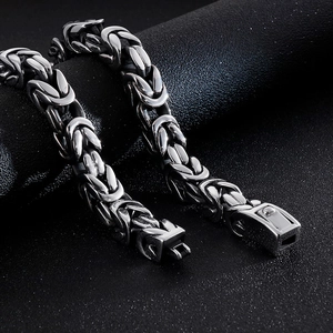 Macro shot of silver Byzantine chain links with a secure fold-over clasp on dark background