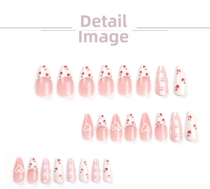 Detail view of pink press-on nails with strawberry art, heart patterns, and pearl accents
