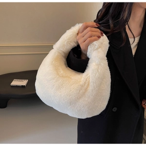 Gros plan sur la texture du sac à main en peluche blanche porté sur un manteau noir