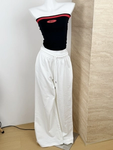 Detail of white wide-leg sweatpants with drawstring waist and black off-shoulder crop top