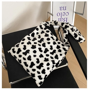 Detail of soft plush tote bag with cow print pattern on a minimalist chair