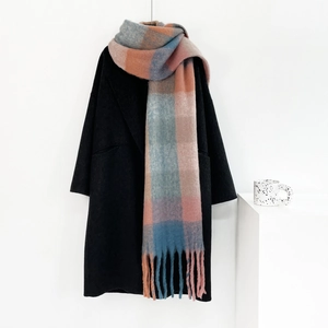 Detail of plaid mohair scarf with tassels styled on a black wool coat for autumn