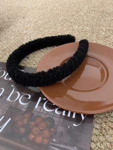 Detailed close-up of a soft black plush headband on a decorative brown tray