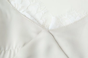 Detailed close-up of grey satin fabric with delicate white eyelash lace on V-neckline