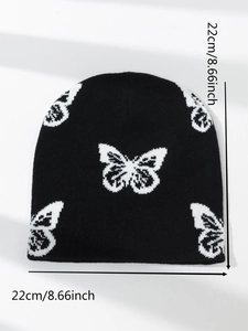 Close-up of a black knitted beanie with white butterfly patterns showing 22x22cm dimensions