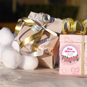 Detail of Happy Mother's Day sticker on pink heart gift box with decorative ribbons
