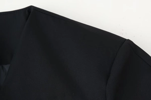 Detail of V-neck collar and puff sleeve seam on a black woven blazer jacket