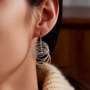 Detailed macro view of tiered gold and silver layered hoop earrings on a model