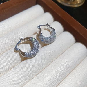 Macro detail of silver-tone hoop earrings with shimmering pavé zircon stones in a jewelry box