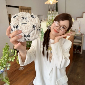 Close-up of white fleece makeup pouch with black bow pattern and green zipper pull