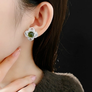 Close-up of green clover stud earrings with white zircons on a model's ear