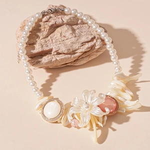 Resin flower and faux pearl necklace with rhinestone shell accents on stone background