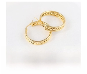 Detailed macro view of triple-layered golden stainless steel hoop earrings with twist texture