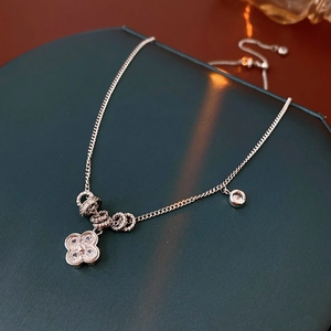 Dettaglio macro di una collana con ciondolo a fiore in argento e zirconi su cofanetto