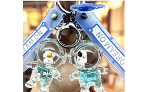 Close-up of astronaut liquid sand keychain with DREAM ON strap and silver hardware