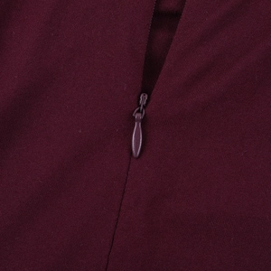 Detailed macro view of burgundy knit fabric and matching invisible zipper on the dress