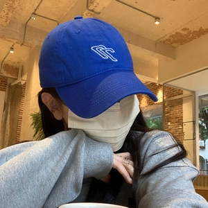 Detail of blue cotton baseball cap with white heart embroidery in a cozy cafe setting