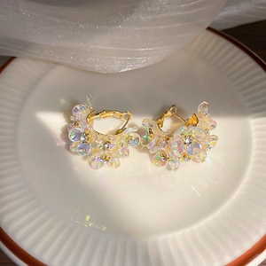 Macro shot of colorful iridescent flower hoop earrings with crystals on a white ceramic plate