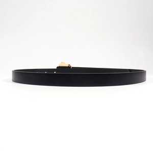 Macro view of women's black leather belt featuring a unique gold cloud-shaped buckle