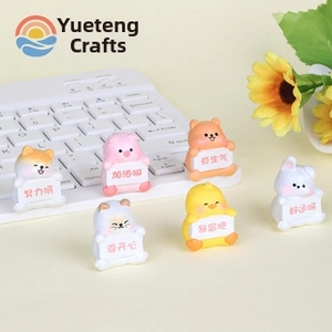 Miniature resin animal figures holding motivational signs on a desk with white keyboard