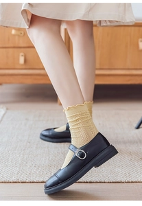Detail of yellow slouch socks with lace trim paired with black Mary Jane shoes