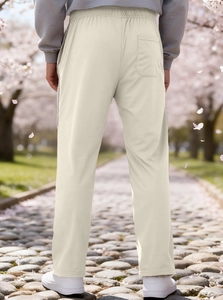 Outdoor back view of men's beige straight-leg sweatpants featuring an elastic waist and pocket