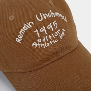 Dettaglio del ricamo bianco su un cappellino da baseball in twill di cotone marrone
