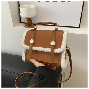 Detail view of vintage brown bag with white faux fur trim and gold metal buckles