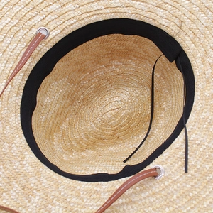 Detailed interior of straw sun hat showing black sweatband and adjustable drawstring