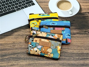 Dettaglio di tre mini pochette in tela a cartoni con doppia cerniera e gancio in metallo