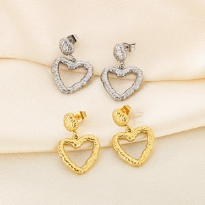 Detail view of gold and silver heart earrings with irregular lava texture on silk fabric