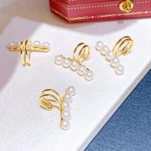Elegant gold-tone ear bone cuff with five white freshwater pearls on a textured background