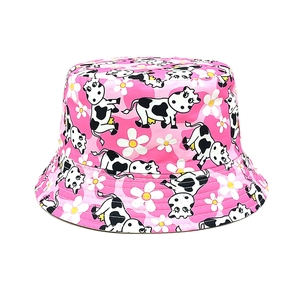 Détail du motif de vache et petites fleurs blanches sur le bord du chapeau rose